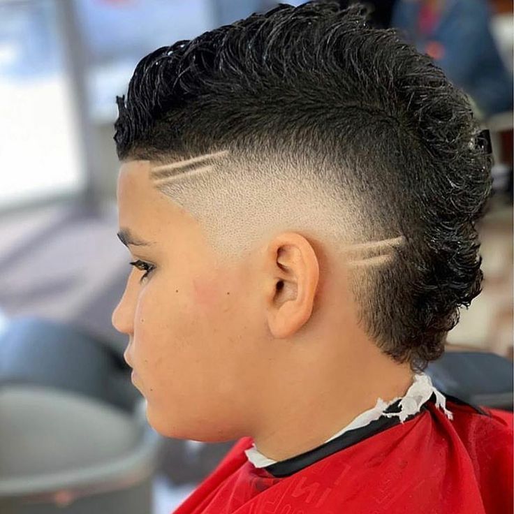 Cortes modernos 2026 para niños: mohawk rizado con fade y dos líneas laterales