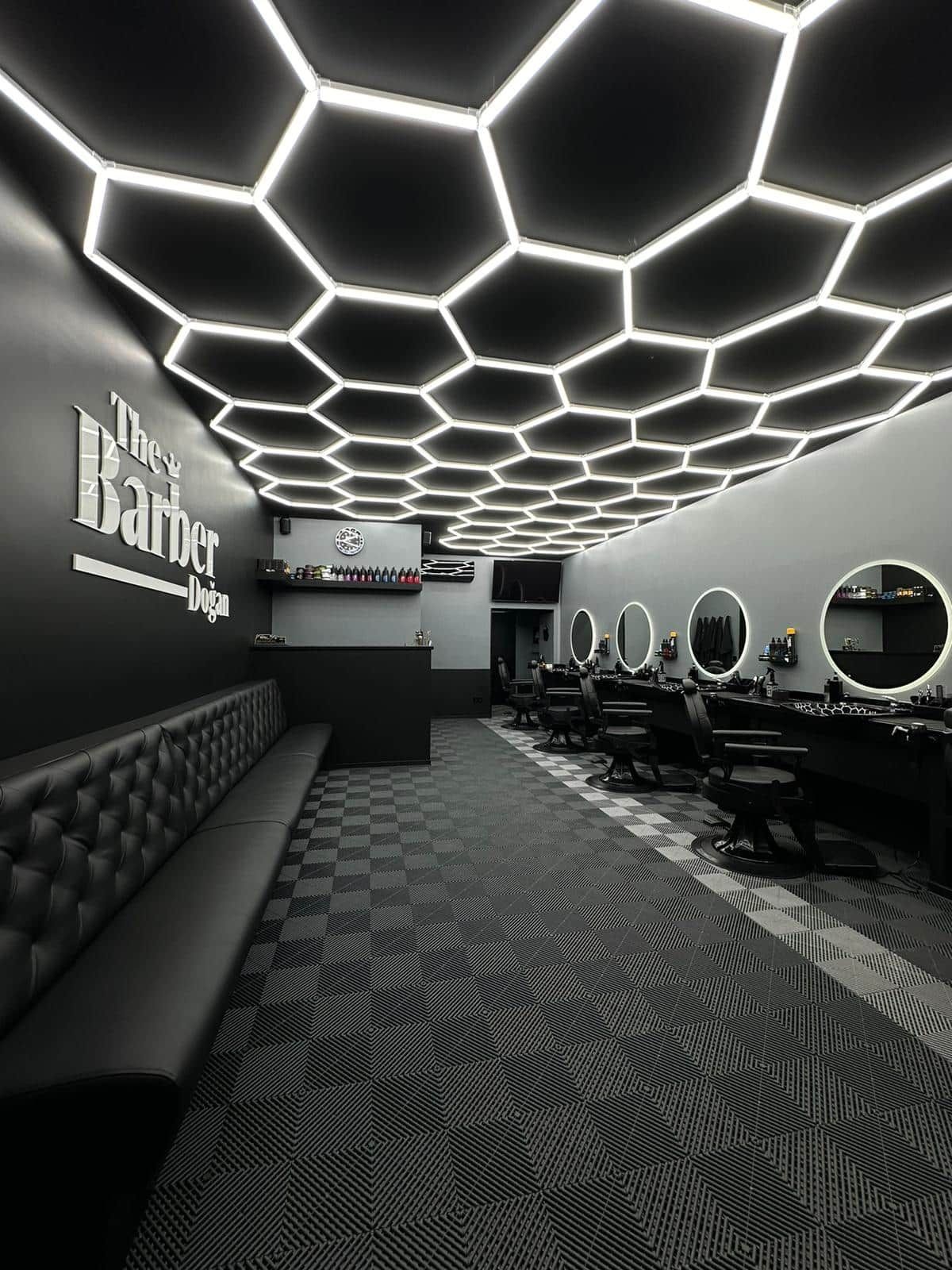 Minimalist black and white barbershop with hexagonal LED lighting, black chairs and checkered floor in grays