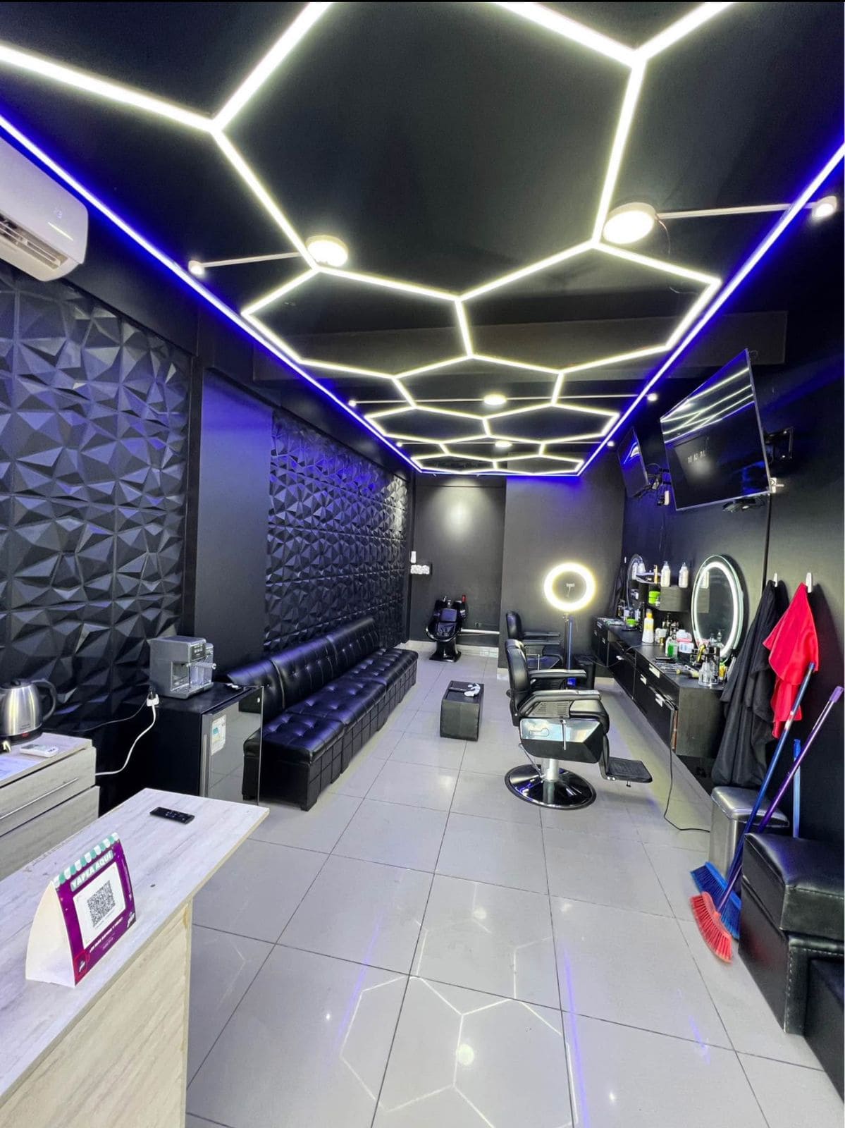 Barbería moderna futurista con iluminación LED hexagonal, paneles 3D en las paredes y ambiente tecnológico