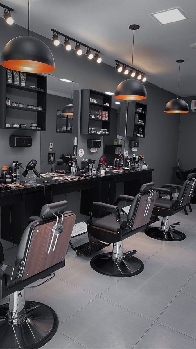 Barbería profesional minimalista con iluminación de carril, lámparas negras con interior naranja y organización impecable